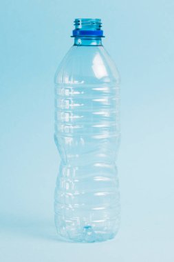 Mavi arka planda şeffaf plastik şişe. Toprak günü kavramı, sıfır atık ve plastik geri dönüşümü