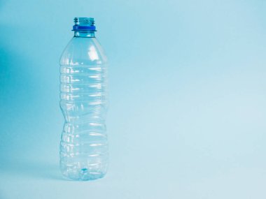 Mavi arka planda şeffaf plastik şişe. Toprak günü kavramı, sıfır atık ve plastik geri dönüşümü