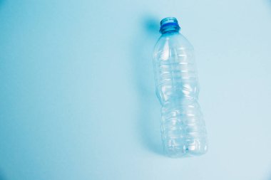 Mavi arka planda şeffaf plastik şişe. Toprak günü kavramı, sıfır atık ve plastik geri dönüşümü