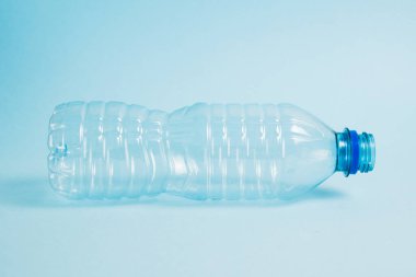 Mavi arka planda şeffaf plastik şişe. Toprak günü kavramı, sıfır atık ve plastik geri dönüşümü