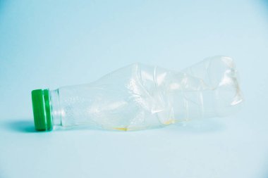 Mavi arka planda bir içki için plastik meyve suyu şişesi kullanmış. Toprak günü kavramı, sıfır atık ve plastik geri dönüşümü