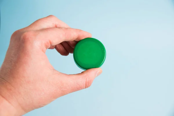 Plastic cap from a disposable plastic bottle in a woman\'s hand. Concept of earth day, zero waste and plastic recycling