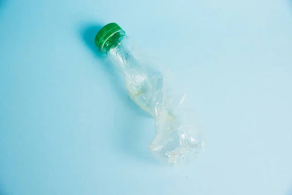 Used plastic bottle of juice for a drink on a blue background. Concept of earth day, zero waste and plastic recycling