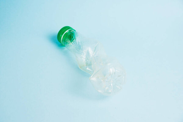 Used plastic bottle of juice for a drink on a blue background. Concept of earth day, zero waste and plastic recycling
