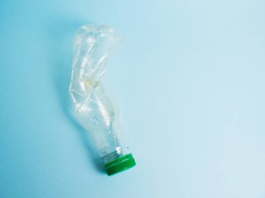 Mavi arka planda bir içki için plastik meyve suyu şişesi kullanmış. Toprak günü kavramı, sıfır atık ve plastik geri dönüşümü