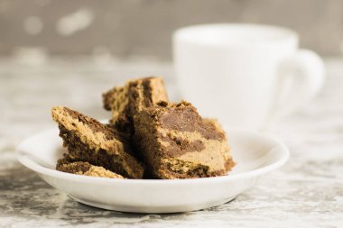 Beyaz bir tabakta kakaolu nefis helva ve açık gri arka planda bir fincan espresso..