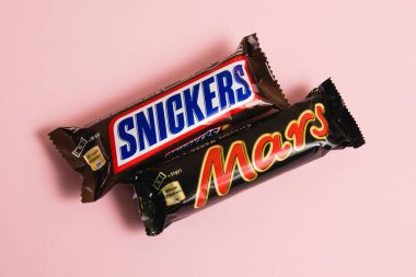 Ukrayna, Chernihiv, 26 Nisan 2023: Mars ve Snickers çikolataları pembe arka planda paketler halinde.