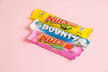 Ukrayna, Chernihiv, 26 Nisan 2023: Pembe arka planda parlak paketler halinde fındık ve çikolata.