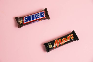 Ukrayna, Chernihiv, 26 Nisan 2023: Mars ve Snickers çikolataları pembe arka planda paketler halinde.