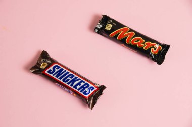 Ukrayna, Chernihiv, 26 Nisan 2023: Mars ve Snickers çikolataları pembe arka planda paketler halinde.