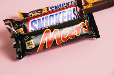 Ukrayna, Chernihiv, 26 Nisan 2023: Mars ve Snickers çikolataları pembe arka planda paketler halinde.