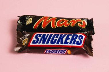 Ukrayna, Chernihiv, 26 Nisan 2023: Mars ve Snickers çikolataları pembe arka planda paketler halinde.