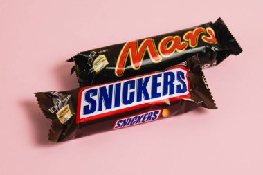 Ukrayna, Chernihiv, 26 Nisan 2023: Mars ve Snickers çikolataları pembe arka planda paketler halinde.