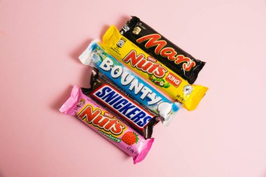 Ukrayna, Chernihiv, 26 Nisan 2023: Fındık, Mars, Snickers ve Bounty çikolataları pembe arka planda parlak ambalajda,.