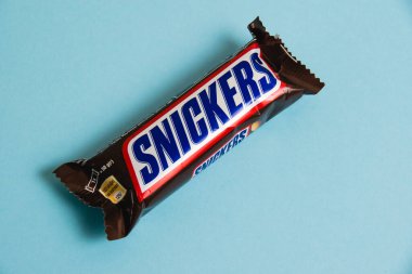 Ukrayna, Chernihiv, 26 Nisan 2023: Lezzetli Snickers çikolatası mavi arka planda yer fıstığı paketinde.