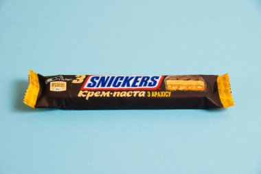 Ukrayna, Chernihiv, 26 Nisan 2023: Lezzetli Snickers çikolatası, mavi arkaplanda tuzlu karamel paketinde.