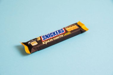 Ukrayna, Chernihiv, 26 Nisan 2023: Lezzetli Snickers çikolatası, mavi arkaplanda tuzlu karamel paketinde.