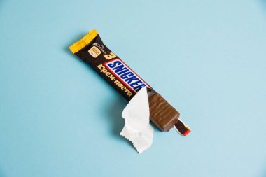 Ukrayna, Chernihiv, 26 Nisan 2023: Lezzetli Snickers çikolatası, mavi arkaplanda tuzlu karamel paketi, açık paket.