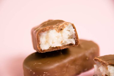 Tatlı çikolata, hindistan cevizi gevreği, makro pembe kağıt arka planda fotokopi alanı ile..