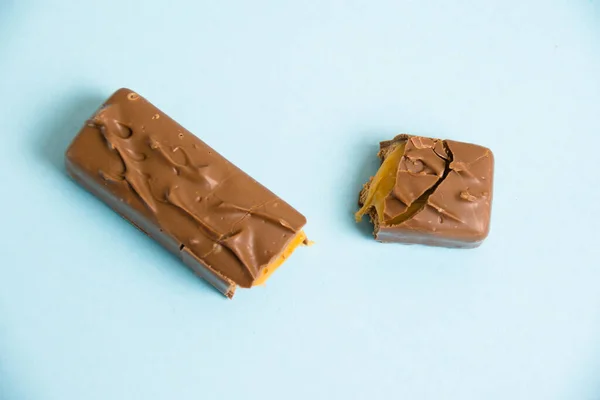 Flatlay Apetitosos Pedaços Barra Chocolate Com Caramelo Fundo Azul — Fotografia de Stock