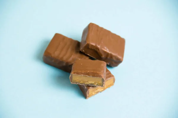 Deliciosas Barras Chocolate Con Caramelo Salado Sobre Fondo Papel Azul —  Fotos de Stock