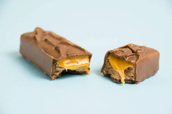 青い背景にキャラメルマクロでチョコレートバーの作品を食欲をそそる — ストック写真