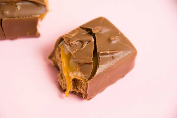 Pedaços Uma Barra Chocolate Com Macro Caramelo Fundo Rosa — Fotografia de Stock