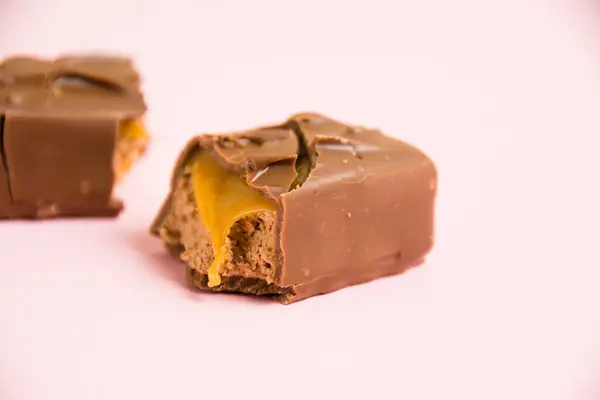 Pedaços Uma Barra Chocolate Com Macro Caramelo Fundo Rosa — Fotografia de Stock