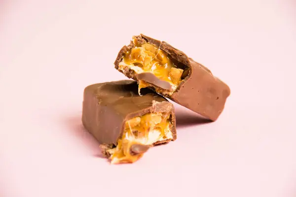 Pedaços Deliciosa Barra Chocolate Com Nougat Caramelo Amendoim Fundo Rosa — Fotografia de Stock