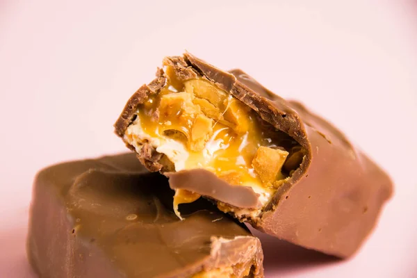 Pedaços Deliciosa Barra Chocolate Com Nougat Caramelo Amendoim Fundo Rosa — Fotografia de Stock