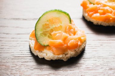 Kırmızı balık ve salatalıklı sandviç. Ahşap zemin üzerinde gevrek pirinç ekmeğine tuzlanmış somon balığı..