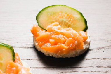 Kırmızı balık ve salatalıklı sandviç. Ahşap zemin üzerinde gevrek pirinç ekmeğine tuzlanmış somon balığı..