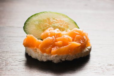 Kırmızı balık ve salatalıklı sandviç. Ahşap zemin üzerinde gevrek pirinç ekmeğine tuzlanmış somon balığı..