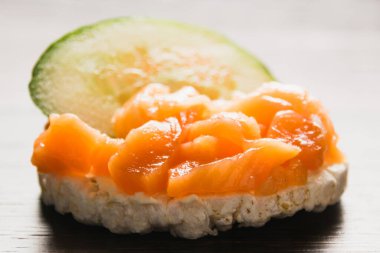 Kırmızı balık ve salatalıklı sandviç. Ahşap zemin üzerinde gevrek pirinç ekmeğine tuzlanmış somon balığı..