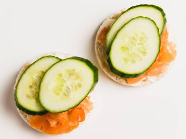 Beyaz arka planda salatalıklı ve kırmızı balıklı yassı sandviçler.