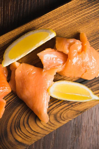 赤い魚のクローズアップ 塩鮭の食欲をそそり 素朴な板の上にジューシーなレモンのスライス — ストック写真