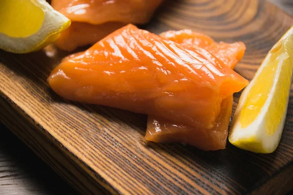 红鱼特写 咸肉鲑鱼片和多汁柠檬片放在乡村木木板上开胃 — 图库照片