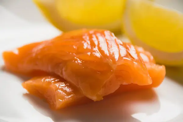 塩紅魚のクローズアップ 白皿にサーモンとレモンのくさびの部分を食欲をそそる — ストック写真