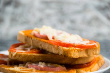 Sosisli, peynirli ve acı soslu lezzetli sandviçler, beyaz ekmek üzerinde, gri tabakta, fotokopi alanı arka planında.
