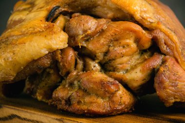 Fırında tavukla pişirilmiş domuz budu. Koyu bir arka planda, ahşap bir kesme tahtasının üzerinde çeşitli pişmiş etler.