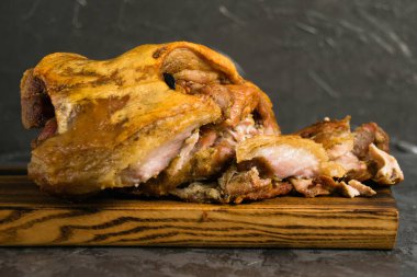 Fırında tavukla pişirilmiş domuz budu. Koyu bir arka planda, ahşap bir kesme tahtasının üzerinde çeşitli pişmiş etler.