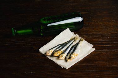 Lezzetli biralar kurutulmuş balıklar ve soğuk biralar karanlık bir arka planda cam bir şişede.