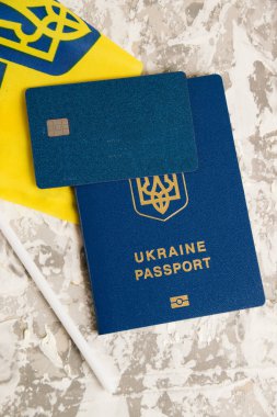 Flatlay, yakın çekimli kredi kartı Ukrayna pasaportu ve ışık masasında bayrak.
