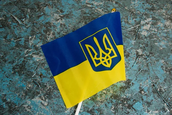 stock image Flag of Ukraine with coat of arms on dark background. The concept of the departure of Ukrainians abroad or the stay of Ukrainian citizens outside the state in connection with the war with Russia