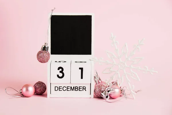 stock image New Year, wooden calendar with the date December 31 and Christmas tree decorations on a pink background. Christmas and New Year celebration concept