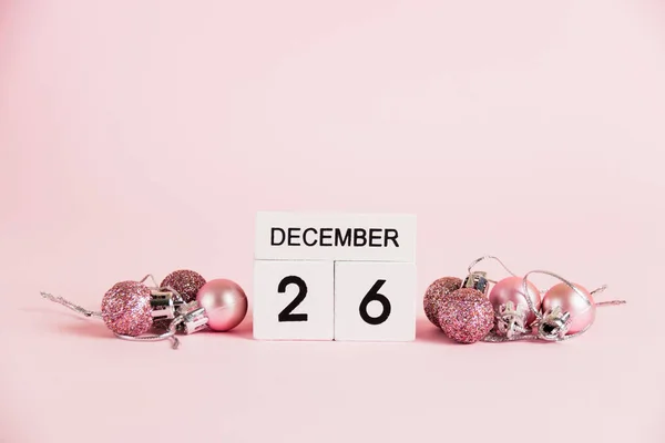 Christmas and Boxing Day, wooden calendar with December 26 date and Christmas tree decorations on pink background. Christmas and New Year celebration concept