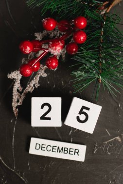 25 Aralık tarihli düz tahta takvim ve koyu dokulu arka plan üzerine Noel süslemesi