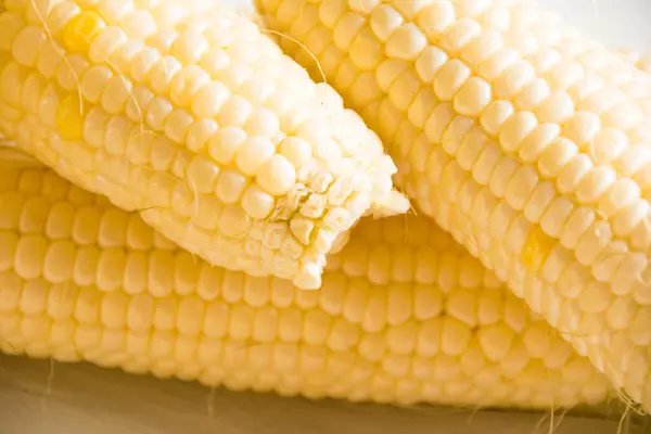 Delicious, sweet white corn on a light table close-up.