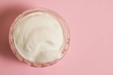 Cam tabakta beyaz sos, pembe arka planda..