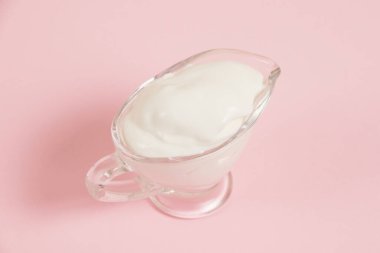 Cam tabakta beyaz sos, pembe arka planda..